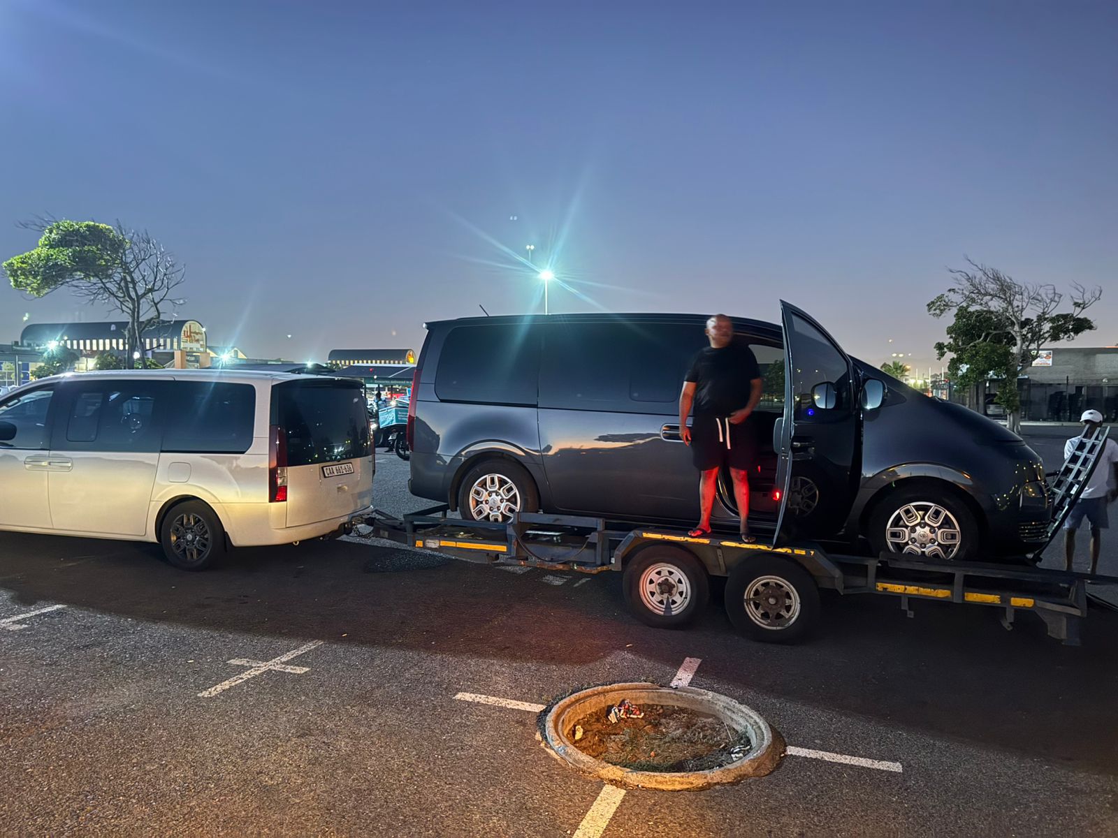 Sir Go Transport fleet vehicles at night with van on trailer